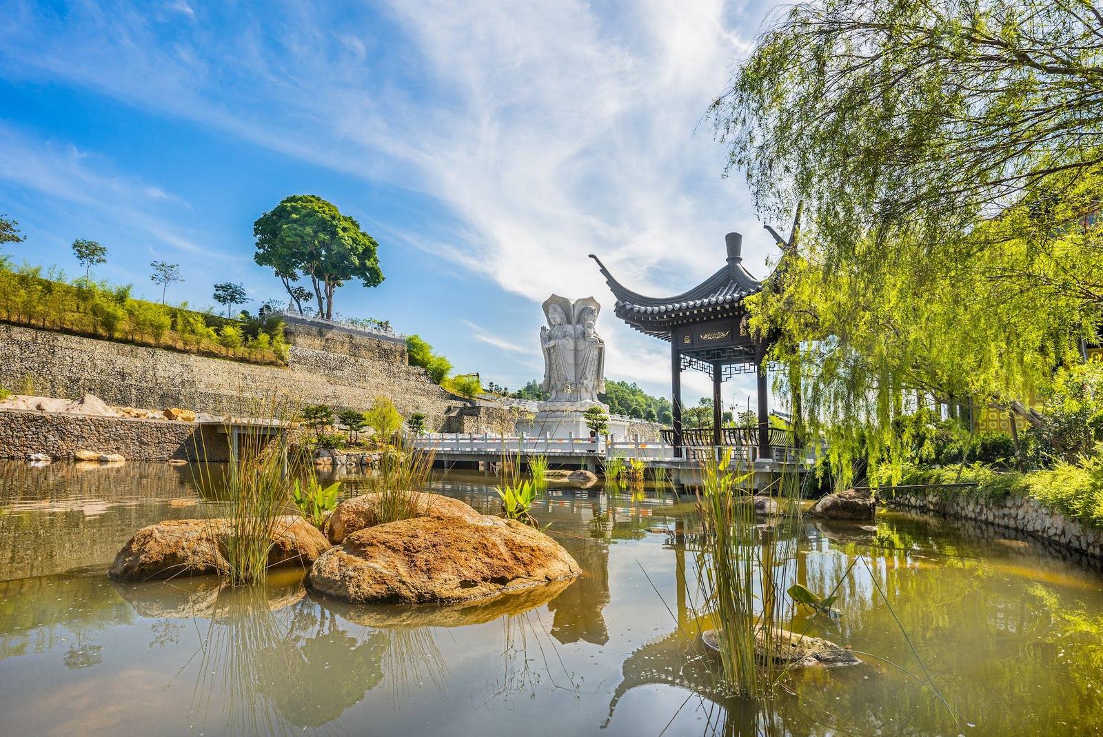 甲板山庄园内的天然湖，湖边有凉亭和柳树，远处是四面观音像